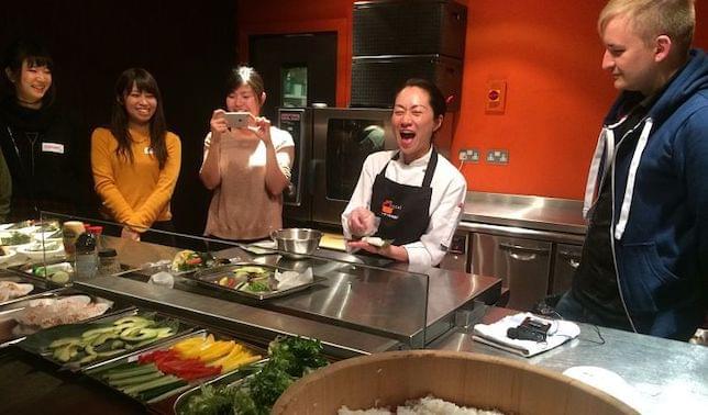 4 Japanese women and a man sharing a joke while preparing Sushi