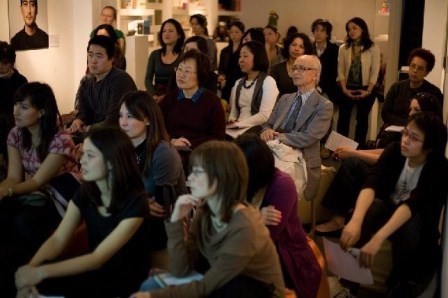 A group of people sitting down in a photo exhibition