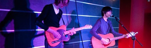 2 men playing guitars on a stage