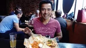 A man sat in a restaurant with a plate of Japanese food and beer