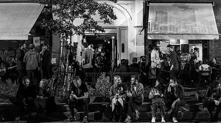 People standing and sitting on terrace outside a cafe
