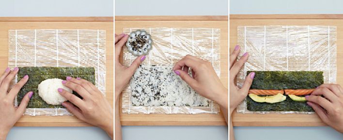 A chef's hands preparing sushi on a wooden board