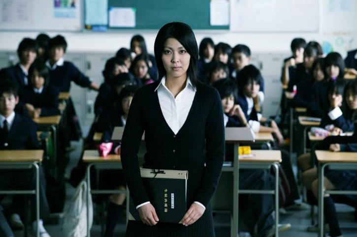 A Japanese girl standing in front of a class of other students