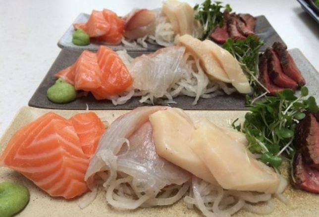 Three plates of sushi and beef on a table