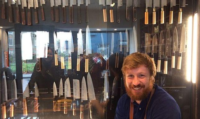 A man sitting in front of a Japanese knife display