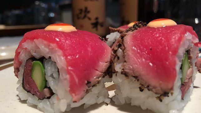 A close up of some beef sushi rolls on a plate