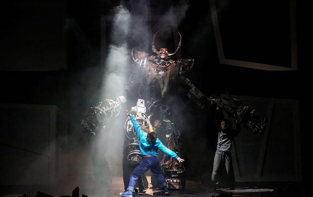 A man dancing on stage in front of a giant robot