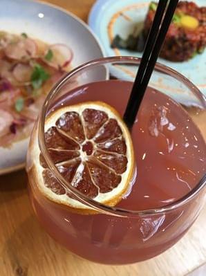 The Londoner sake cocktail in a glass with a slice of lemon and a straw