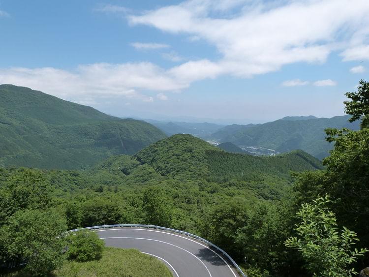 A winding road in the mountains, which are covered in forests
