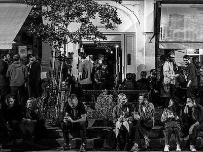 Small groups of people drinking and chatting outside a bar